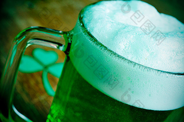 木桌上放着一个玻璃杯子，上面有染色的绿色啤酒和三叶草，是为圣帕特里克日准备的