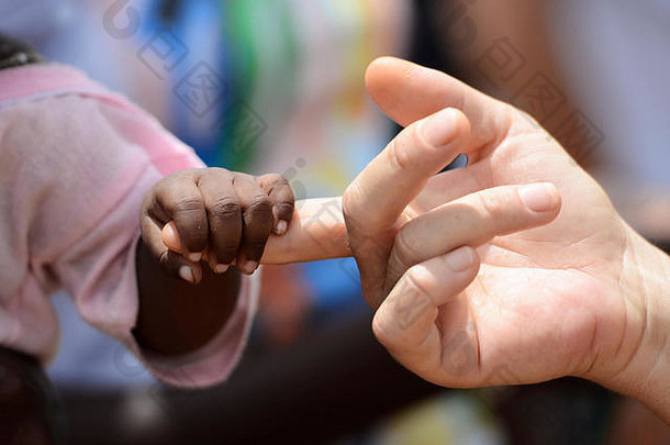 在马里的巴马科，一名黑人和白人妇女与一名非洲土著小女孩手牵手。地球上的和平象征。一张漂亮的照片，有很多p
