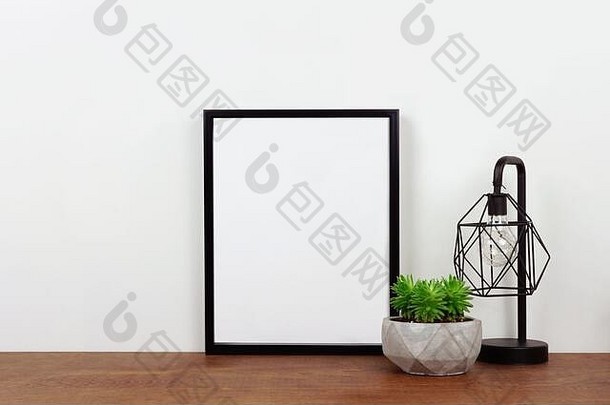 在架子或书桌上模拟黑色框架、多汁植物和工业风格的灯。木架子和白墙。纵向框架方向。