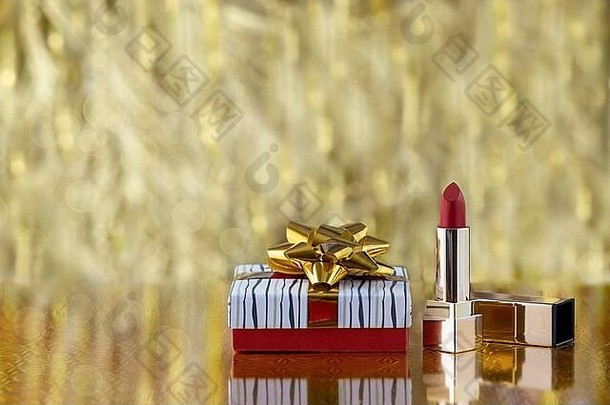 礼品盒与黄和红色唇膏在黄金模糊的背景。假日概念与复制温泉。