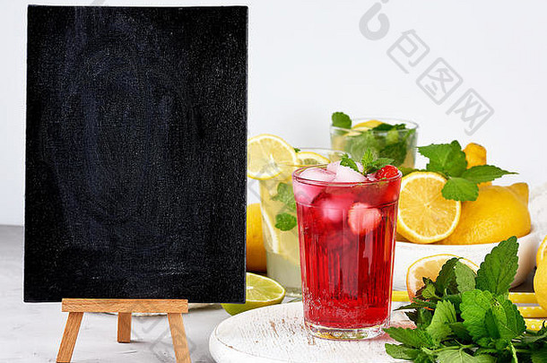 空的黑色粉笔板，用来写一份夏季饮料的，还有一杯浆果柠檬水、新鲜的黄色柠檬和薄荷绿