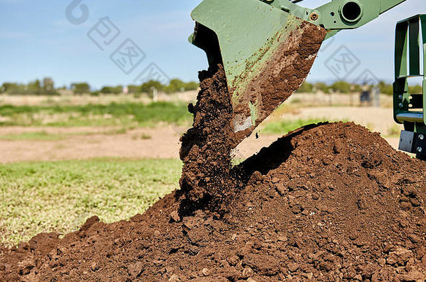 拖拉机铲斗将泥土倾倒到桩上的特写镜头