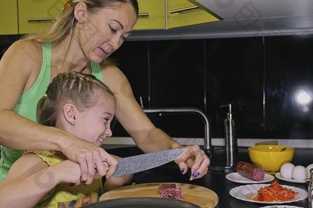 母亲教女儿聪明的女孩学做饭。情妇让孩子们用意大利腊肠做一个那不勒斯鸡蛋煎蛋卷。