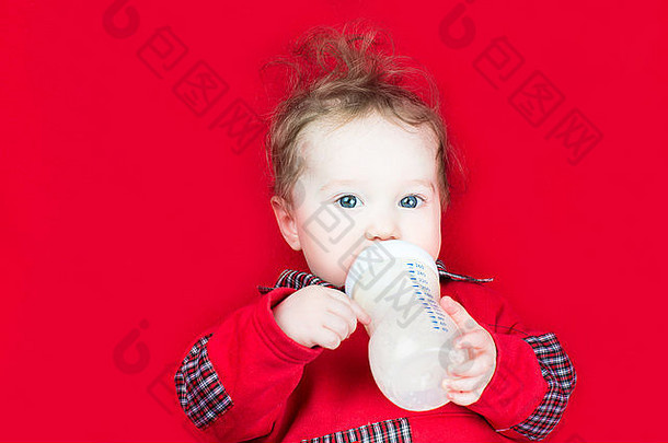 可爱的小婴儿在红色毯子上喝牛奶