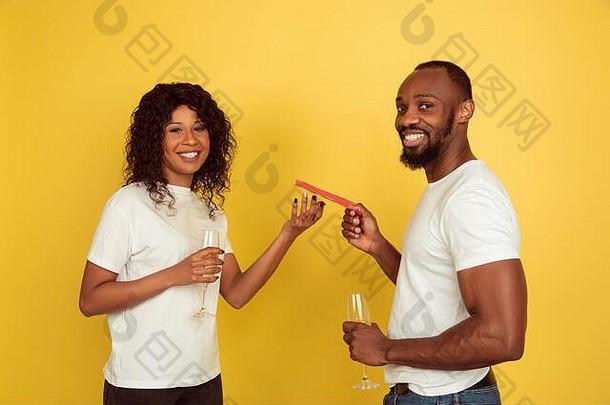 给红包。<strong>情人节</strong>庆祝活动，一对幸福的非裔美国夫妇被隔离在黄色的工作室背景上。人类情感的概念，面部表情，爱情，关系，浪漫的节日。