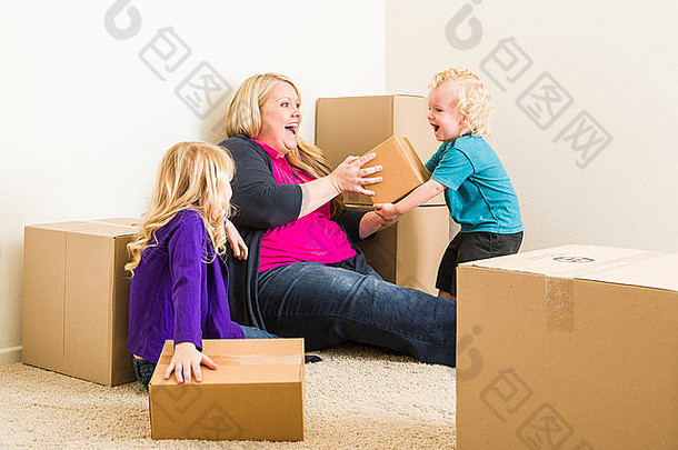 一家人在空荡荡的房间里玩移动的箱子。