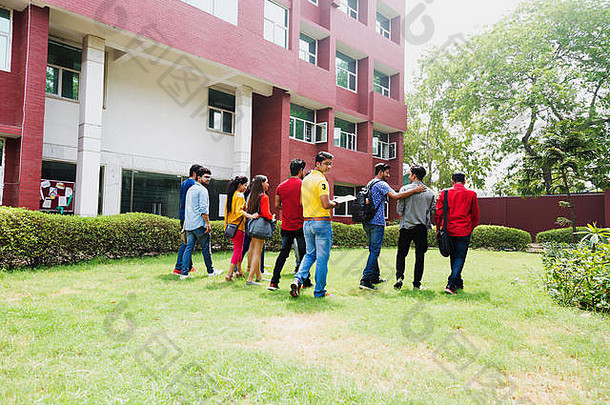 一群年轻的大学生男女朋友在校园外的大学大楼里和书一起散步