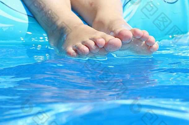 夏日炎炎烈日下，游泳池边孩子的脚在水中嬉戏