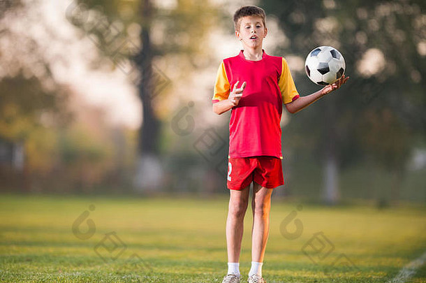 拿着足球的小男孩摆姿势拍照