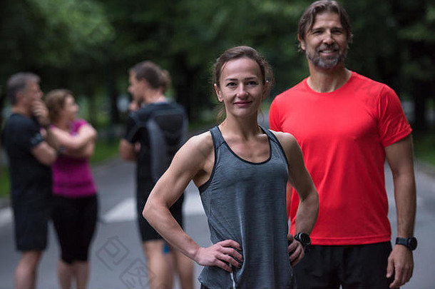 一对健康的慢跑夫妇的肖像，背景是他们<strong>跑步</strong>团队的其他成员
