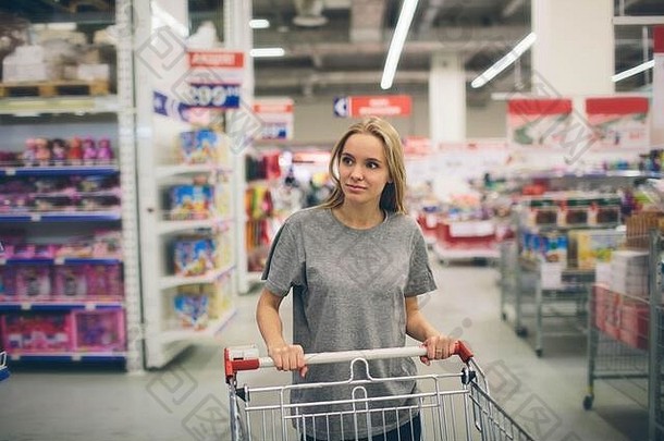 超市里好奇的女人。在商场购物的小女孩在想买什么