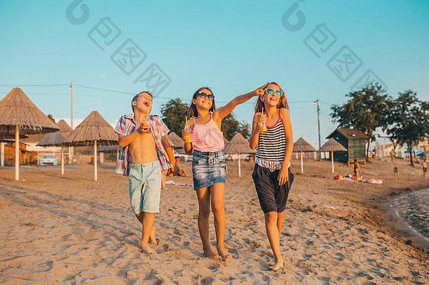快乐的孩子们在沙滩上散步时玩得很开心。暑期旅游概念图