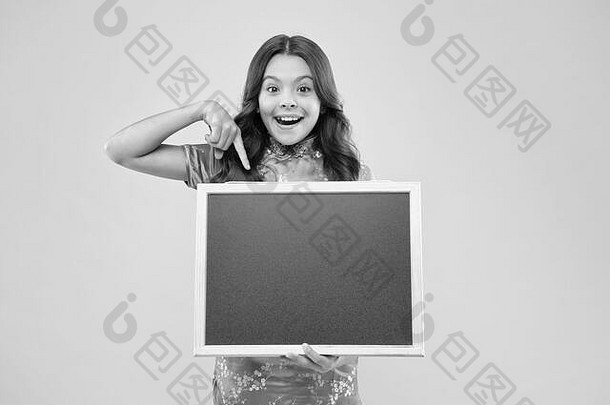 为你的文本。黑板为广告文字，空间。快乐女孩拿着黑板粉红色的背景。快乐的孩子举着广告牌。那个小学生得到黑板上课。