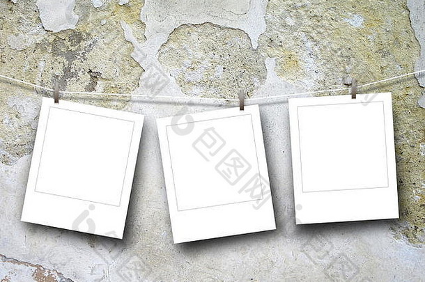 三个空白方形即时相框的特写镜头，用钉子挂在刮伤的混凝土墙背景上