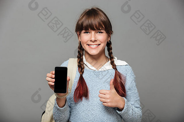 肖像年轻的愉快的女学生显示空白屏幕移动电话孤立的灰色的背景