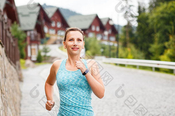 在山坡镇鹅卵石铺成的街道上慢跑的年轻微笑的健身妇女