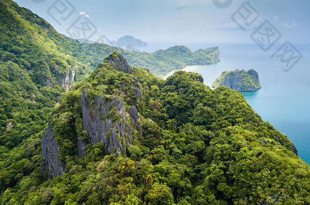 无人驾驶飞机俯瞰一个遥远的热带岛屿，岛上有参差不齐的石灰岩悬崖和暴风雨天空中的丛林
