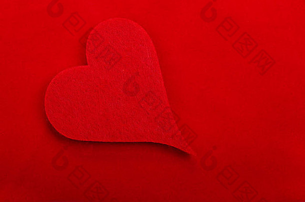 红色织物心脏隔离在红色背景上。为您的设计腾出空间。