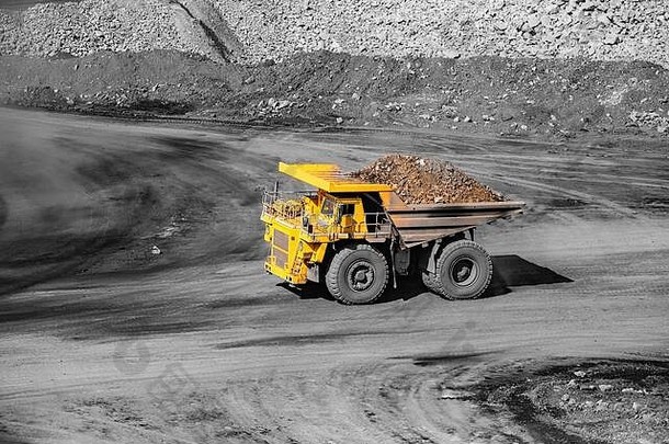 黄金矿石的大型黄色矿用卡车运输。露天采矿业