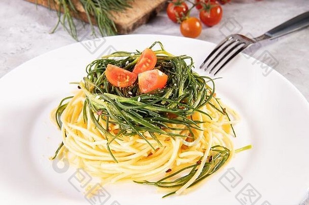 意大利意大利通心粉，意大利的一种春季蔬菜，配料和叉子放在灰色背景的白色盘子上
