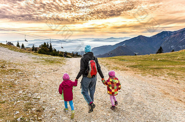 家庭徒步旅行山滑雪坡日落妈妈。双胞胎孩子们徒步旅行脚路径自然阿尔卑斯山脉山行为