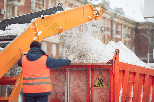 除雪拖拉机除雪机在自卸卡车上装载一堆雪。暴风雪或降雪后，户外雪犁城市街道。
