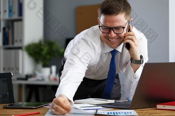 办公室里快乐的人在笔记本电脑旁打电话