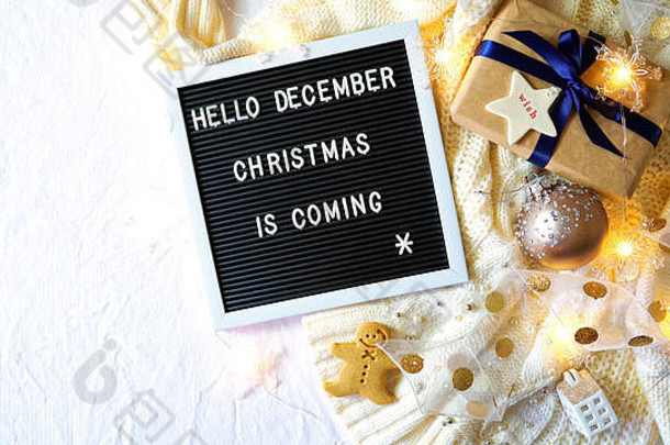 在时尚的圣诞公寓里，舒适地躺在床上或室内，穿着暖和的毛衣、礼物和写着“Hello December，圣诞节就要到了，wi