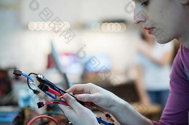 一名年轻女子在一家电脑修理店使用连接电缆和usb线。
