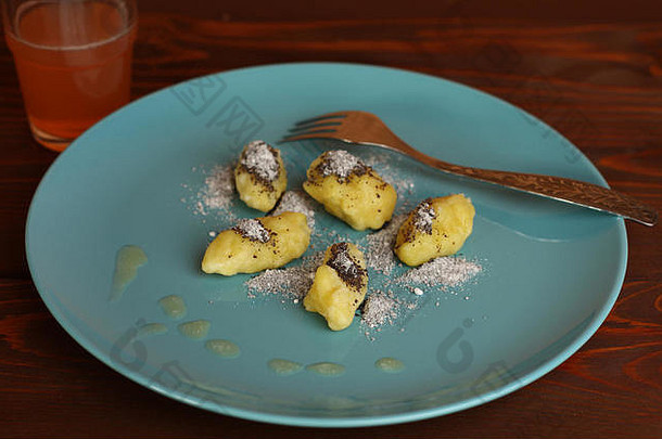 用融化的黄油和籽放在蓝色盘子上的甘薯粉面条和果汁。