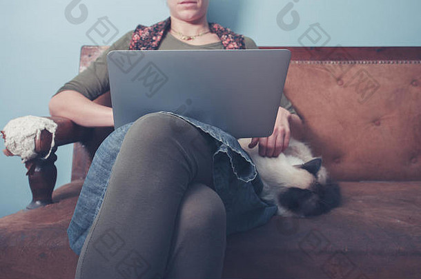 年轻的女人坐着沙发工作移动PC<strong>猫</strong>