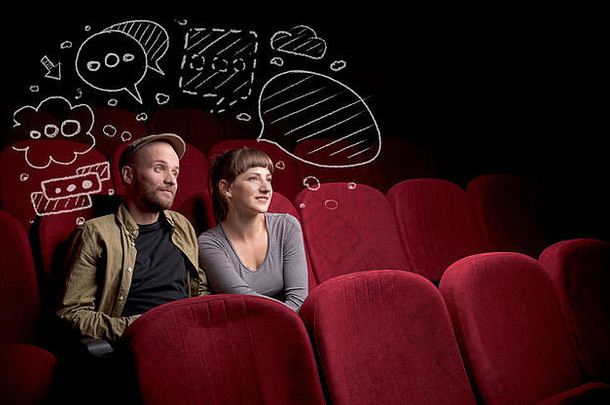 一对年轻可爱的情侣坐在电影院里，一边吃着爆米花一边看<strong>涂鸦图片</strong>的电影