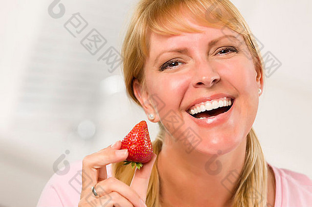在<strong>厨房</strong>里拿着草莓的金发碧眼美女。