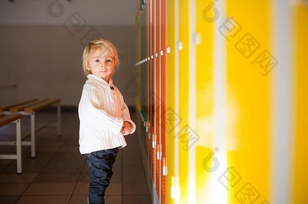 冬天，站在幼儿园或学校走廊储物柜前的金发小男孩