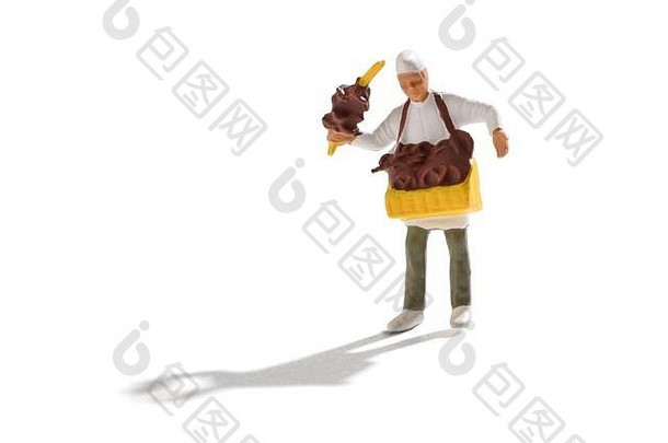 微型椒盐卷饼销售商，头戴白色面包帽，身穿制服，脖子上围着一盘酥脆的传统德国糕点，其他人则陈列在一张桌子上