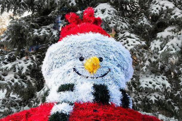 雪地里的圣诞树背景上，用金属丝做成的欢快的雪人。拼贴画新年装饰和节日中的圣诞雪人角色