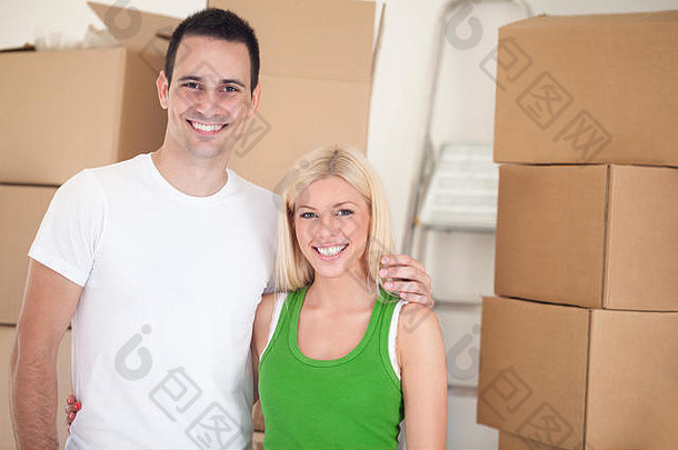 背景为移动盒子的新居中微笑着相爱的夫妇的肖像