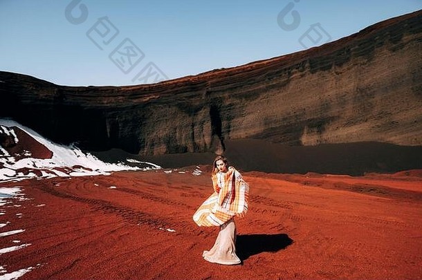 女孩挥动毯子。一个穿着金色婚纱的新娘模特的肖像，在一个黄红色的沙质采石场中，在一个火山口中