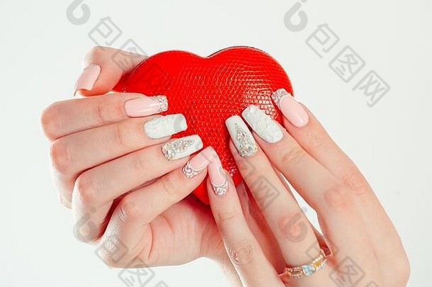 爱修指甲艺术概念美手持有红色的心形状的珠宝盒子时尚的柔和的颜色粉红色的珊瑚白色指甲孤立的白色使用
