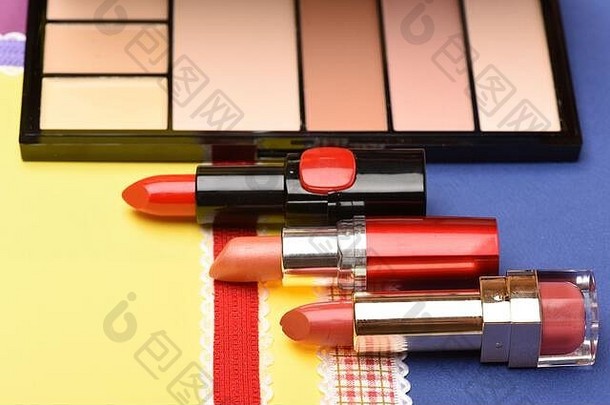 彩色背景上的唇膏和化妆品。眼影、粉剂、遮瑕膏、托盘、化妆用品。