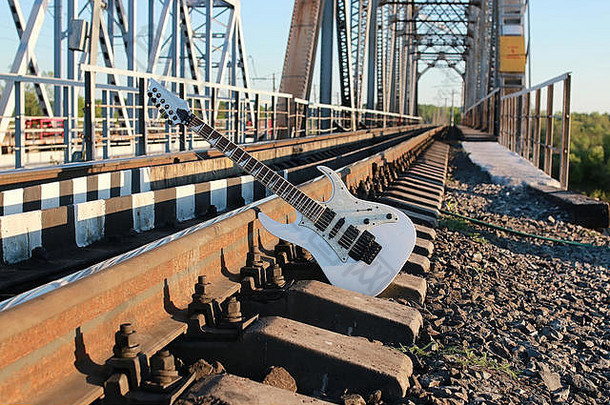 铁轨和石头上的白色电吉他