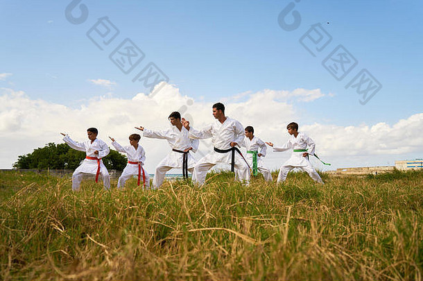 西班牙裔男子和儿童练习空手道和传统武术。近岸海滩战斗模拟