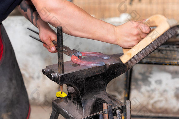 铁匠在铁砧上工作，制作马蹄铁。