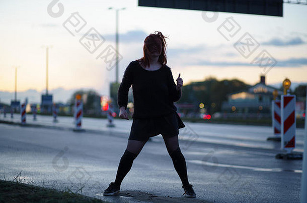 活跃的旅行者舞者女人执行路建设网站日落时间车灯通过穿黑色的裙子温暖的毛衣