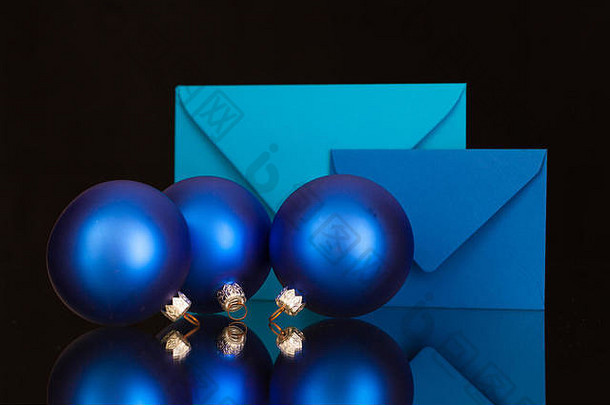黑色玻璃桌上的蓝色信封和圣诞装饰