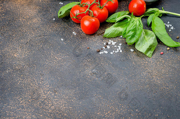 成熟的红色和黄色西红柿、葱和罗勒、大蒜、盐和香料，深色石头背景。俯视图，空间。