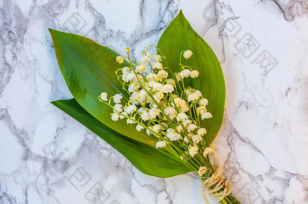 一束美丽的花，散发着山谷百合花或大理石背景上玻璃花瓶中的五月百合花的香味。春夏园林概念。山谷里礼来花的细枝