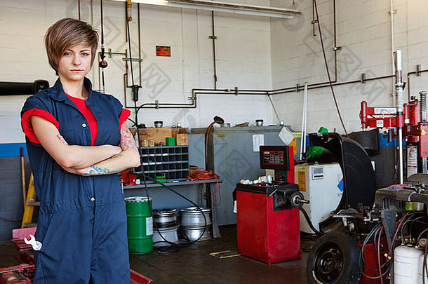 一位自信的年轻女机械师在<strong>车库</strong>里双臂交叉的画像