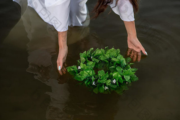 水里穿着白色衣服的女人的特写镜头。在河里戴着花环的艺术女人。湖里湿漉漉的女巫