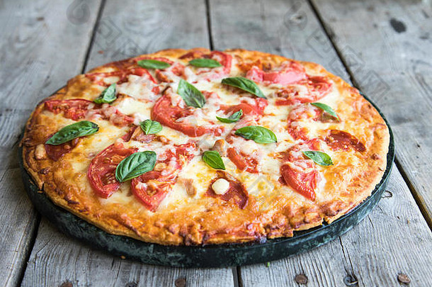 热自制的意大利辣香肠披萨乡村木表格披萨番茄奶酪罗勒复制空间